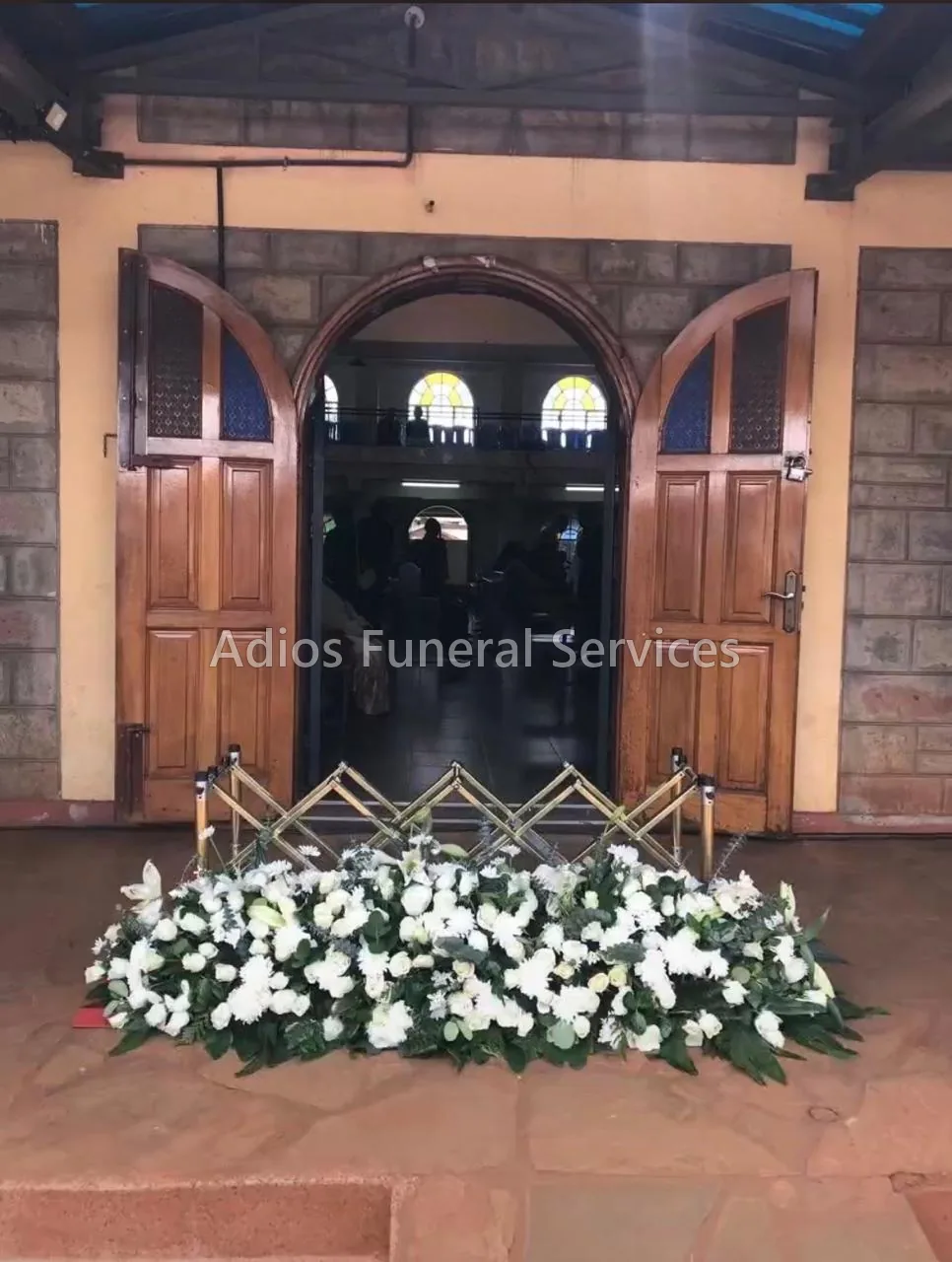 White casket spray and church trolley at a church entrance